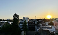 the sun is setting over a city with buildings in the background